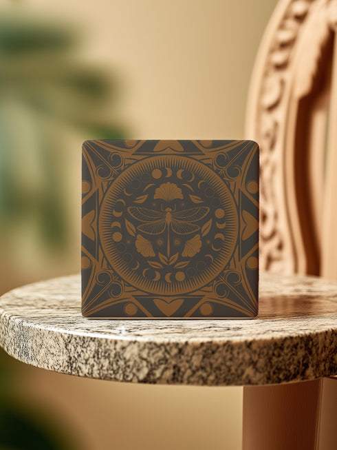 Square ceramic coaster featuring a detailed copper dragonfly design centered in a medallion, surrounded by moon phases and Art Nouveau patterns on a charcoal black background, with cork backing.